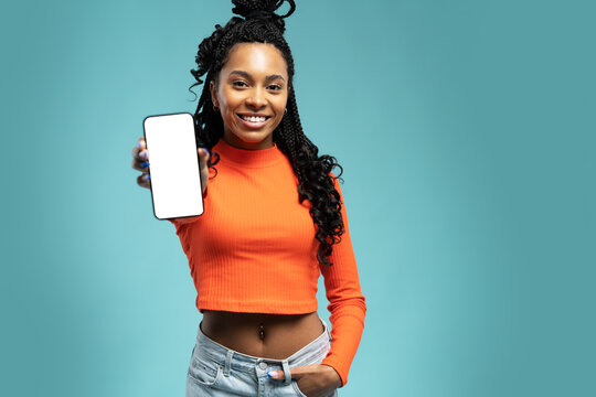 Excited Lady Pointing Finger At Smartphone In Her Hand, Emotionally Reacting To New App Standing Isolated Over Blue