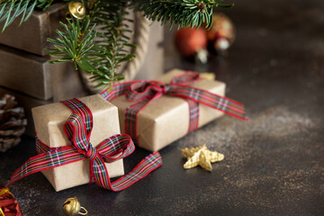 Wrapped gift boxes between Christmas decorations, pine cones and green fir branches