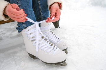 A young happy woman puts on ice skates. Winter sport. Ice skating. Winter.