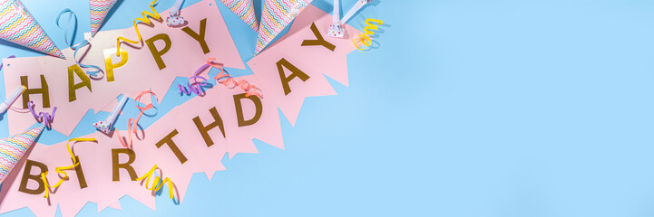 Birthday greeting card simple background. Garland streamer with the inscription HAPPY BIRTHDAY on a blue background, with accessories for celebration holiday, banner background copy space flatlay
