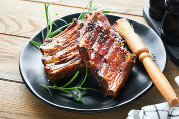 Grilled and smoked pork ribs with barbeque sauce on an old vintage wooden cutting board on old wooden table background. Tasty snack to beer. American food concept. Top view.