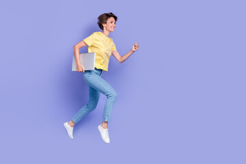 Full body photo of active cheerful lady hold netbook jump running isolated on violet color...