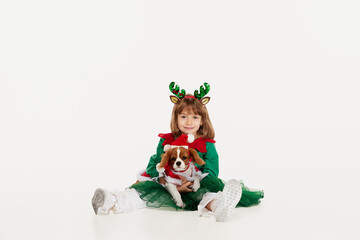 Portrait of beautiful little girl, child posing with dog isolated over white studio background. Merry Christmas