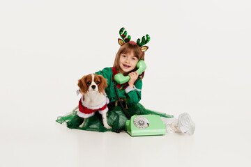 Portrait of beautiful little girl, child posing with dog isolated over white studio background. Calling Santa Claus