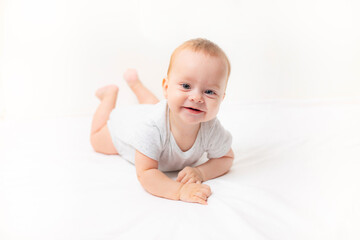 The baby lies on a white background and smiles at the camera . Advertising of children's goods. A child on a white background. Happy baby. The smile of a child. Children 's article .