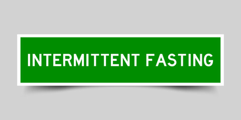 Green color square shape sticker label with word intermittent fasting on gray background