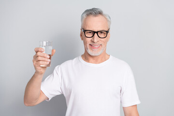 Portrait of satisfied glad person hold water glass toothy smile look camera isolated on grey color...