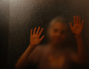 Blur. The girl looks through the glass. Child behind glass.