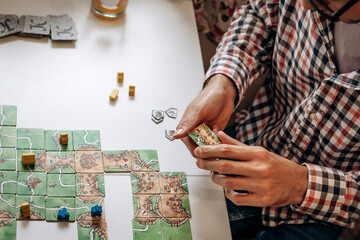 A group of young people play board games at home in the kitchen.Hands close-up.Time together.Stay...