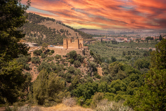 The Kasbah castle from the Middle Atlas and the Tadla plain of Morocco protecting and overlooking the Moroccan city of Beni Mellal-Jenifra under an orange sky. Concept Morocco, castle, city, landscape