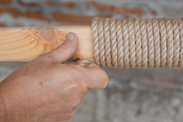 Making decor with twine. A man winds twine around a piece of wood