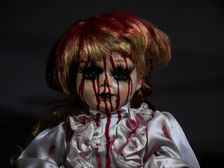 horror style porcelain blonde hair doll face in darkness covered in blood