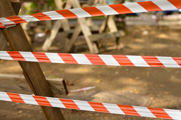 Red and white warning tape stretched across a blurred background with ground. Protection tape...