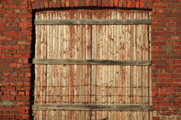 A locked wooden door against a red brick wall.