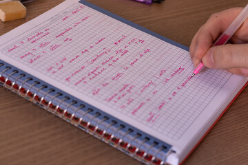 Man doing English homework on a notebook writing with a pen