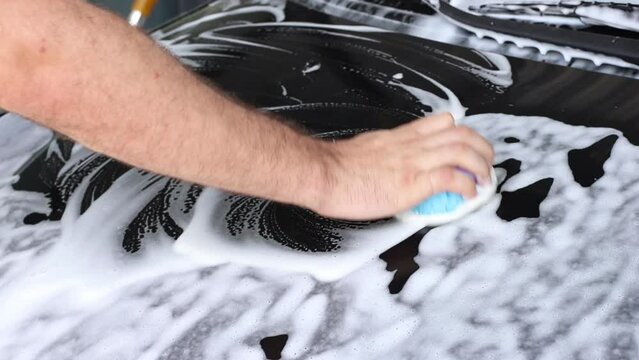someone washes a car with foam at a car wash