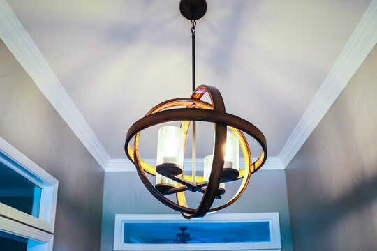 A suspended hanging orb light fixture in a front entrance of an Acadian style home or house