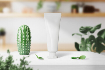 Clean minimal cream tube packaging mockup standing on top table with cactus decor ant plant