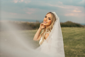 Portrait of a brunette model girl in the role of a bride. Beautiful face, portrait at sunset in...