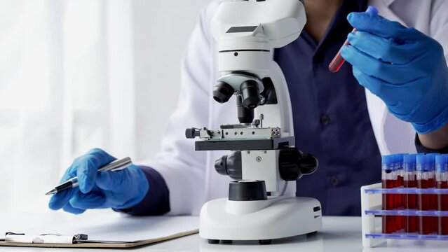 Doctor hand taking a blood sample tube from a rack with machines of analysis in the lab background, Technician holding blood tube test in the research laboratory.