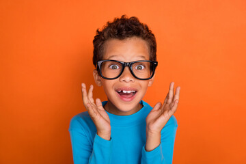 Photo portrait of cute small boy astonished new glasses can see excited dressed stylish blue garment isolated on orange color background