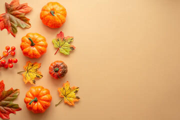 Autumn flat lay background with copy space at color paper. Pumpkins, leaves and fall decorations.