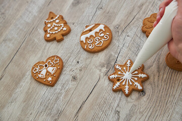 Close up of drawing gingerbread Christmas snowflake sugar cookie on wooden table background with white icing