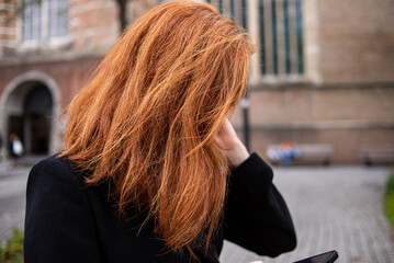 Fototapeta na wymiar Woman with red hair using smartphone on street