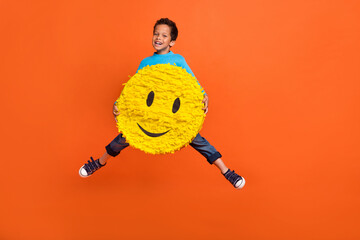 Full body photo of cute little boy jump hold big smile emoji influencer good mood wear trendy blue look isolated on orange color background