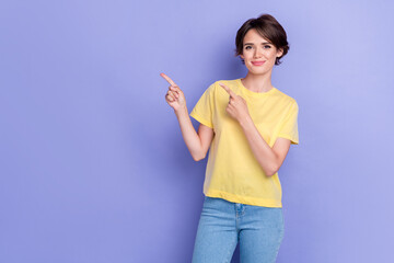 Photo of young attractive adorable pretty girl wear yellow t-shirt cute smile fingers pointing empty space recommendation isolated on violet color background