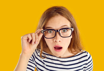 Funny surprised student girl. Young blonde woman in glasses sees something unbelievable and looks at camera with shocked, stunned, astounded, impressed face expression. Closeup, close up headshot - obrazy, fototapety, plakaty