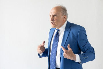 Portrait of grumpy mature businessman pointing at himself and arguing with opponent. Senior manager...