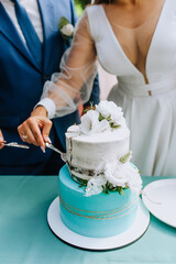 The bride and groom cut the sweet, delicious wedding cake on the table with a knife into large pieces on a plate at the ceremony. Photography, dessert.