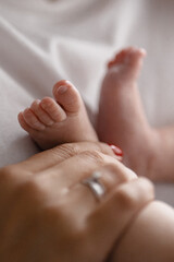 Mother holding newborn baby feet in hands. Mom taking care about infant child after taking bath.