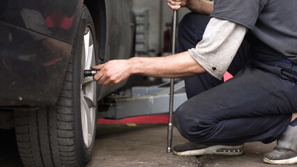 auto mechanic spins the wheel of the car. car workshop.