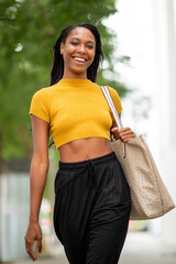 Cheerful black woman with handbag outdoors in city