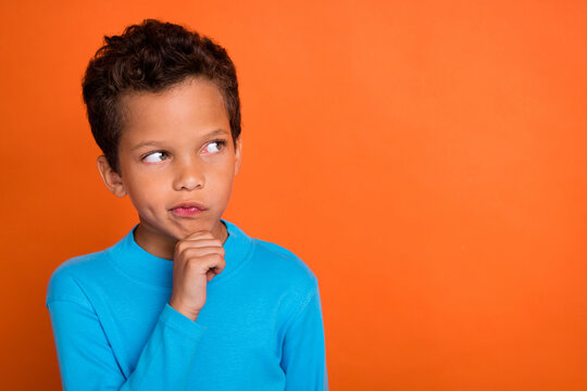 Photo of concentrated focused boy look empty space consider decision dilemma choice choose empty space isolated on orange color background