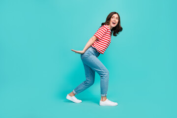 Fototapeta na wymiar Full length photo of crazy pretty lady arm hold big size ad carry look empty space striped stylish wear isolated on cyan color background
