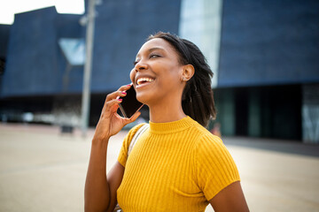 Happy black woman talking on mobile phone outdoors in city