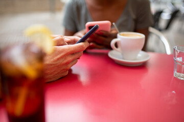 Fototapeta na wymiar Two diverse friends using mobile phone at coffee shop