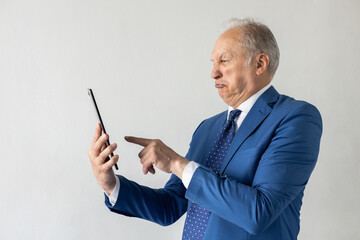 Portrait of depressed mature businessman surfing internet on digital tablet. Senior manager wearing formalwear using touchpad with resentful expression against white background. Bad news concept