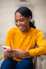 Cheerful black woman text messaging using mobile phone