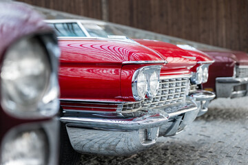 Many classic red vintage old american cars parked in row at garage, exhibition of fest. Close-up...