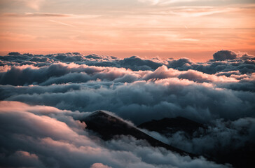 Picos de montaña apareciendo sobre mar de nubes. - obrazy, fototapety, plakaty