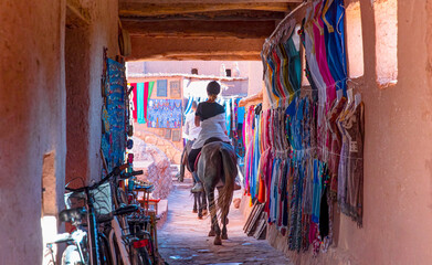 Fototapeta na wymiar Beautiful woman rider who rides a horse in the streets of Ait Ben Haddou near Ouarzazate river - Atlas Mountains, Morocco, North Africa 