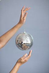 Woman hands holding disco ball against gray background. Event concept. 