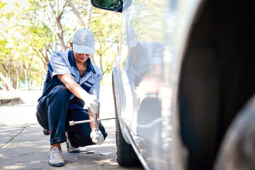 Fototapeta na wymiar auto repair technician Changing the wheels of a car for a customer who has an accident with a broken tire on the road. Transportation concept. service business