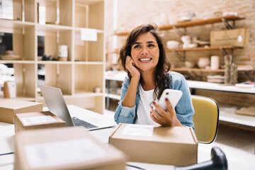 Cheerful online store owner thinking of new creative ideas for her business