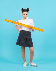 School girl holding measure for geometry lesson, isolated on blue background. Measuring equipment. Student study math.
