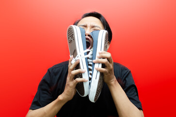 Ew. It's so gross. A young Asian man in a t-shirt stands over an empty red background while...